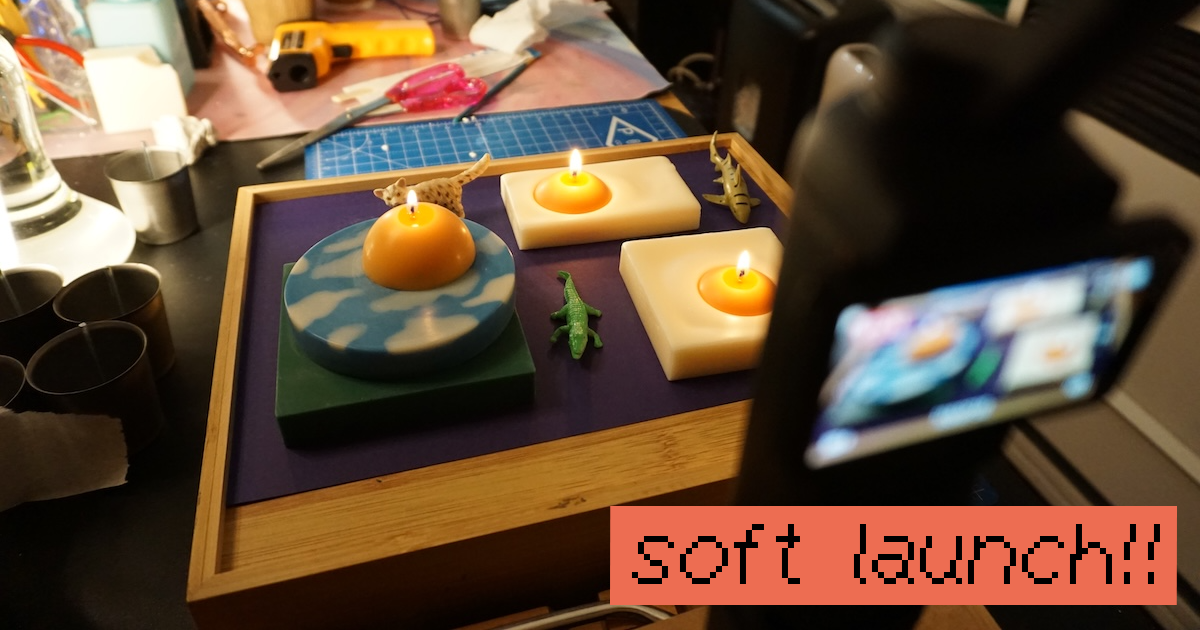 photo of my 'touching grass' and 'sunny side up' candles lit and i'm recording them because it's a light test i did a few months ago in my candle workshop